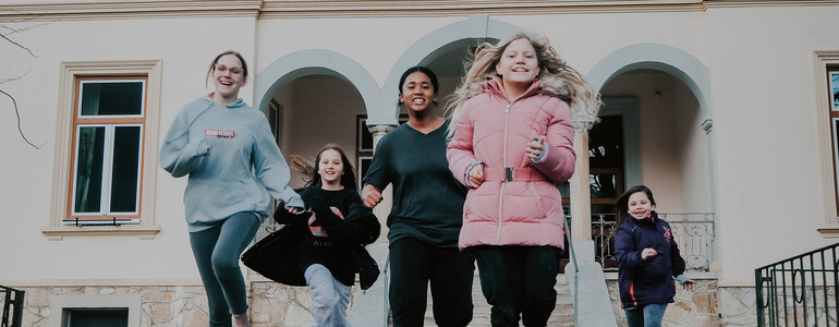 Kinder und Jugendliche unserer sozialpädagogischen Einrichtung, das Haus Antonius in Treffen, laufen aus dem Eingang des Hauses.