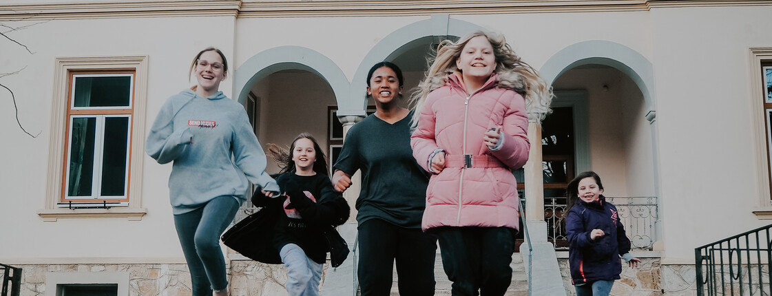 Kinder und Jugendliche unserer sozialpädagogischen Einrichtung, das Haus Antonius in Treffen, laufen aus dem Eingang des Hauses.