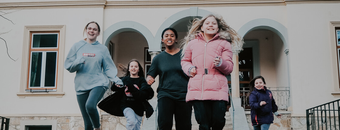 Kinder und Jugendliche unserer sozialpädagogischen Einrichtung, das Haus Antonius in Treffen, laufen aus dem Eingang des Hauses.