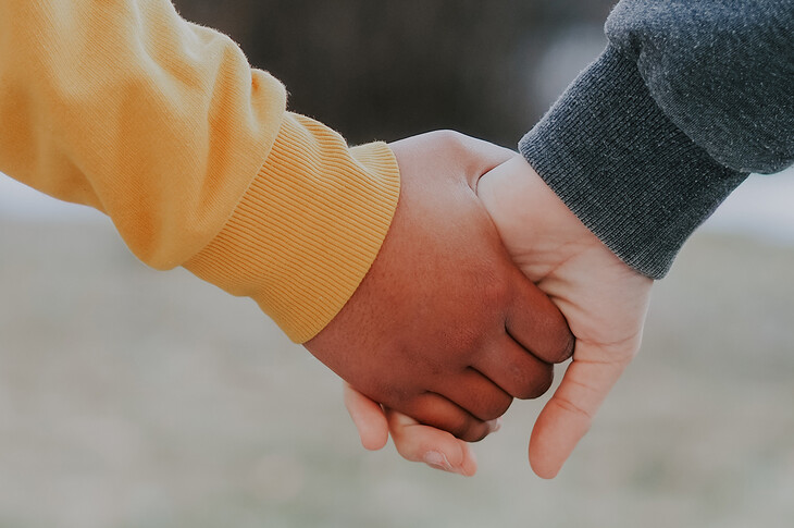 Eine Kinderhand und eine Betreuer*innenhand halten sich.