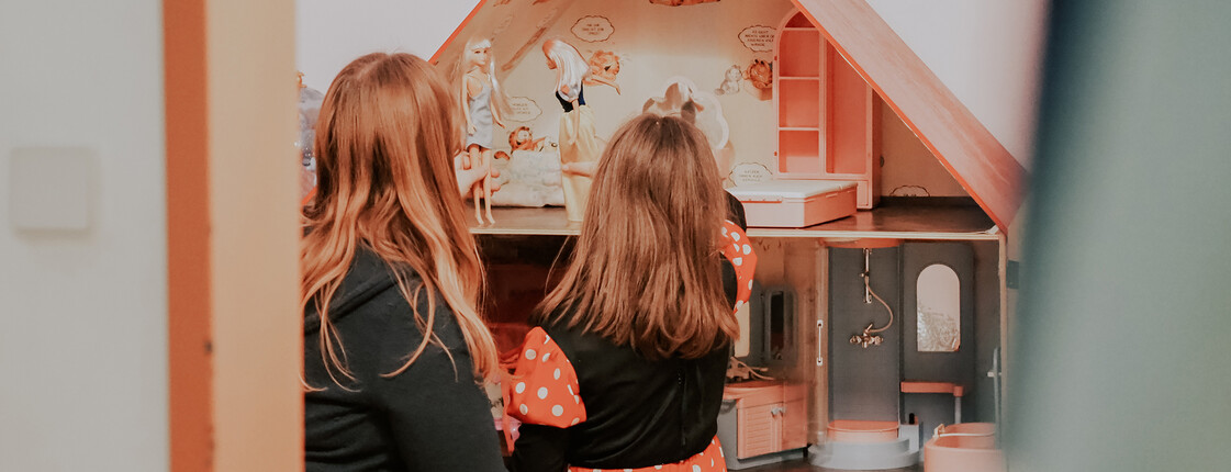 Eine Betreuerin unserer sozialpädagogischen Einrichtung, Haus Antonius in Treffen, spielt mit einem Mädchen im Puppenhaus.